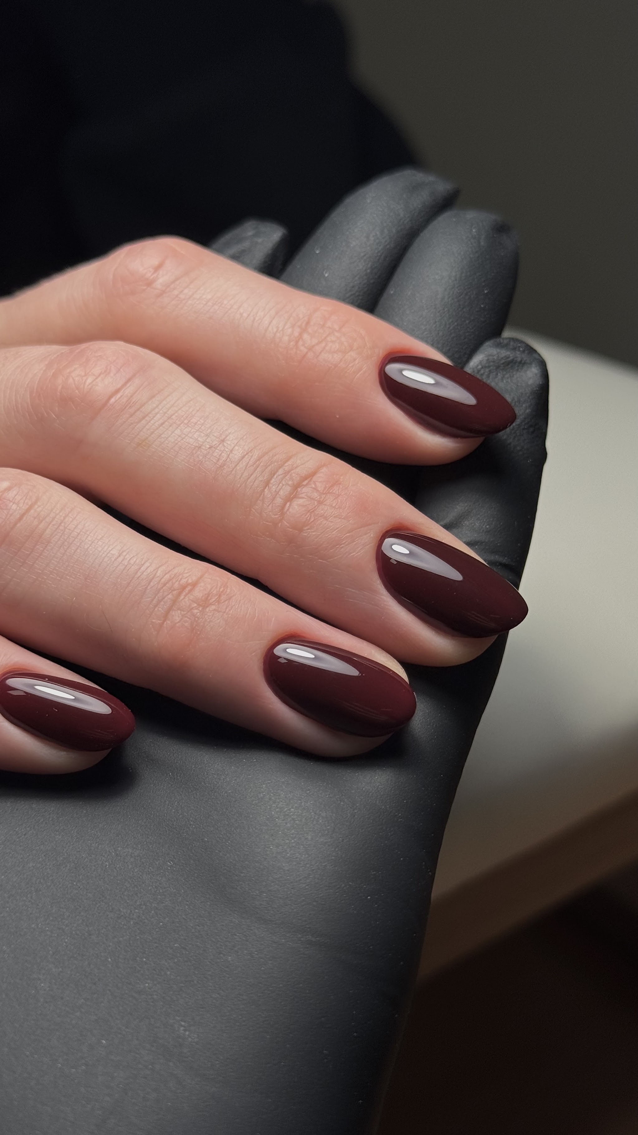 Bordeauxrode nagels op een zwarte handschoen
